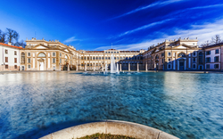 Großer, eleganter Palast mit zentralem Brunnen und blauem Himmel.