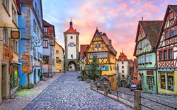 Bunte Fachwerkhäuser in einer gepflasterten Altstadtstraße bei Sonnenuntergang.