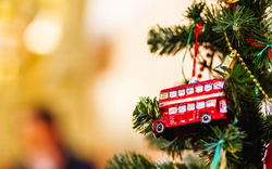 Weihnachtliche Dekoration an einem Tannenbaum mit rotem Doppeldeckerbus in London, Großbritannien.