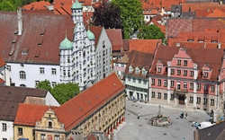 Platz mit historischen Gebäuden und Brunnen, rote Dächer, Vogelperspektive.
