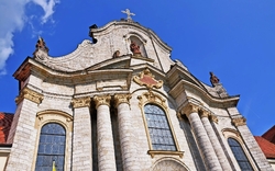 Barocke Kirchenfassade mit Säulen und blauer Himmel.