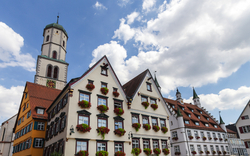 Historische Fachwerkhäuser und Kirchturm bei blauem Himmel.